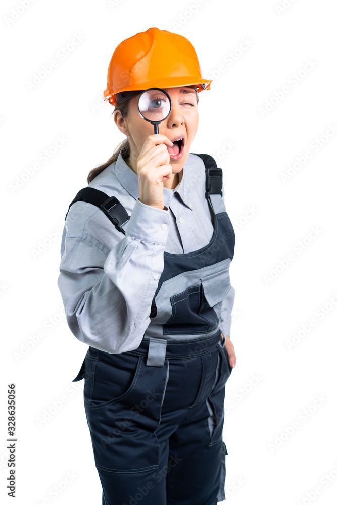 girl construction engineer examines something in a magnifying glass. Isolated girl construction engineer examines something in a magnifying glass. Isolated