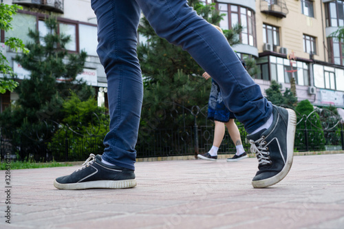 Guy's legs in running in blue pants and blue summer shoes. In the background is a girl in a blue summer dress and low-heeled shoes. The story of how everyone hurries about their business.