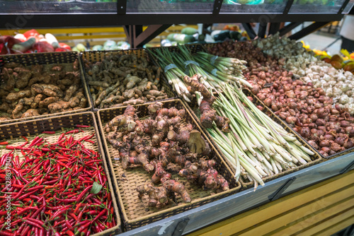 Vegetables on shelves in supermarket with fresh chilli, dry onion, dry ginger, dry citronella...