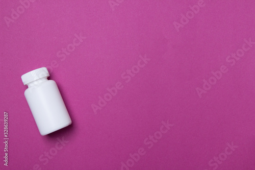 White plastic medical container for pills on purple background with copy space