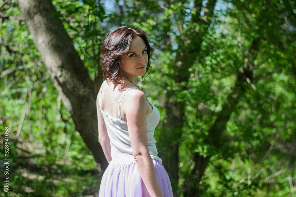 Beautiful young brunette woman posing in a forest among shrubs and trees Beautiful young brunette woman posing in a forest among shrubs and trees