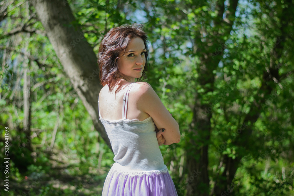 Beautiful young brunette woman posing in a forest among shrubs and trees Beautiful young brunette woman posing in a forest among shrubs and trees