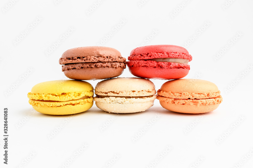 Five sweet French macarons with different aromas, isolated on white, flavours of strawberries, lemon, caramel, vanilla, orange and chocolate, tasty dessert in pastel colors on a table Five sweet French macarons with different aromas, isolated on white, flavours of strawberries, lemon, caramel, vanilla, orange and chocolate, tasty dessert in pastel colors on a table