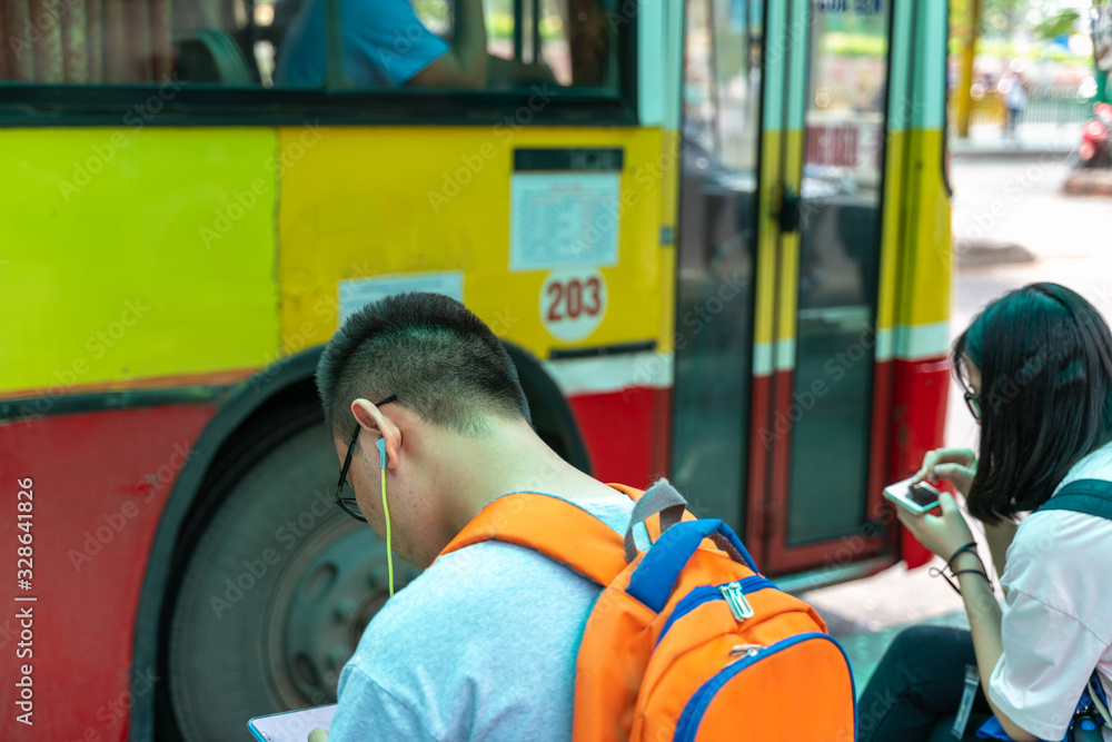 Asian people use smartphone waiting for bus at bus stop Asian people use smartphone waiting for bus at bus stop