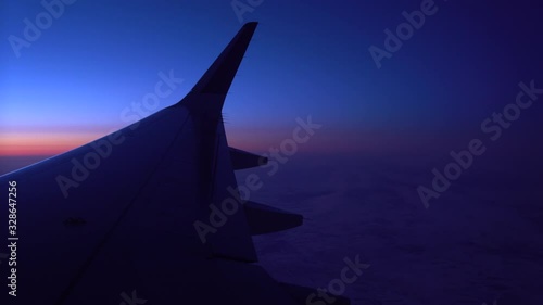 Through the porthole, you can see the wings of the aircraft , which is in the air against the background of clouds, and navigation lights are flashing on the wing. Traveling by plane , night flight, y