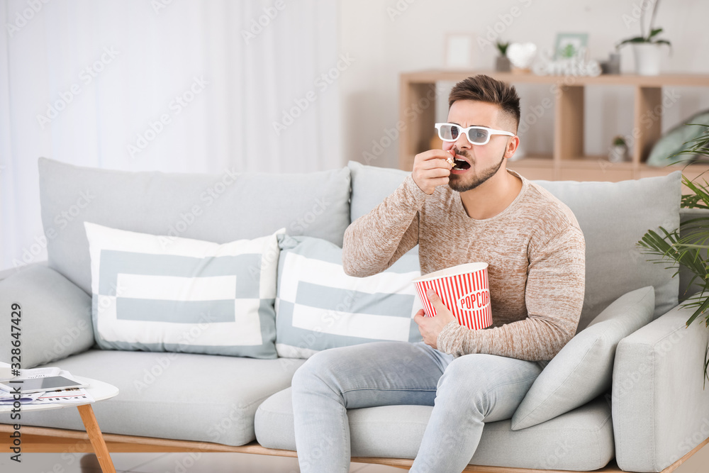 Young man watching movie while sitting on sofa at home Young man watching movie while sitting on sofa at home