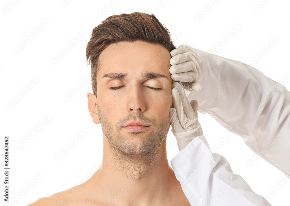 Obraz premium Plastic surgeon touching face of young man on white background