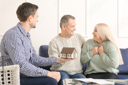 Male real estate agent working with mature couple indoors