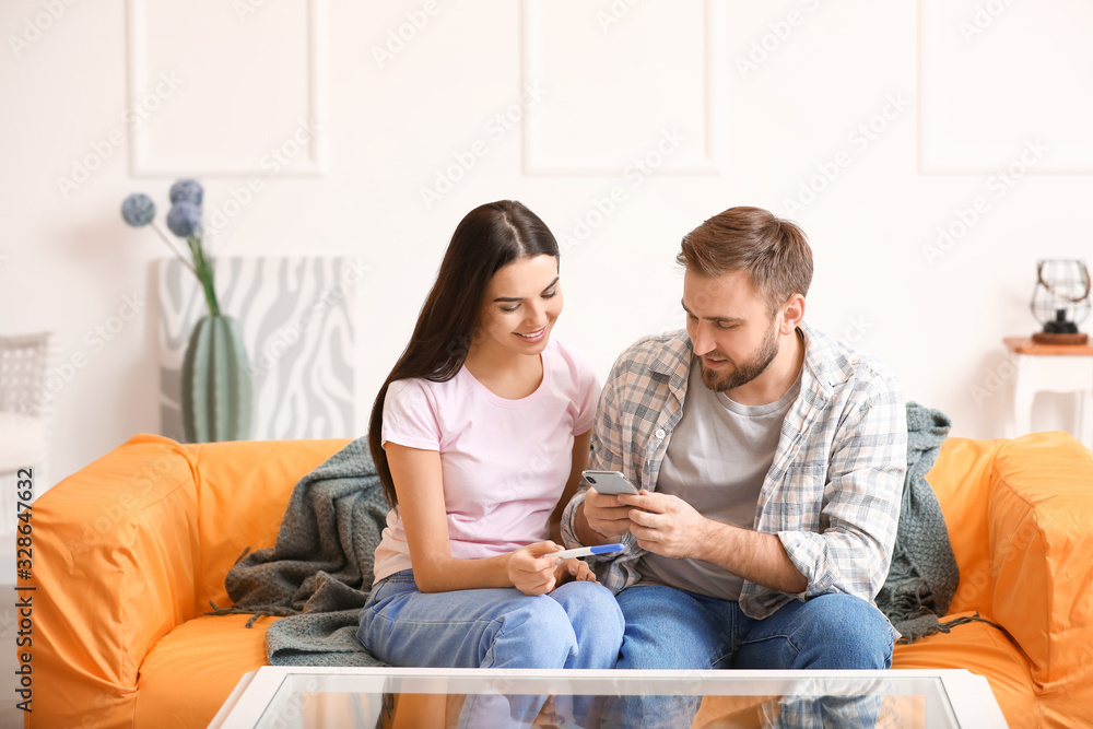 Young couple with pregnancy test and mobile phone at home Young couple with pregnancy test and mobile phone at home