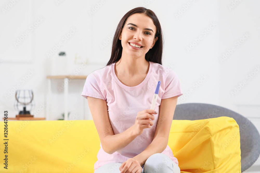 Happy young woman with pregnancy test at home Happy young woman with pregnancy test at home