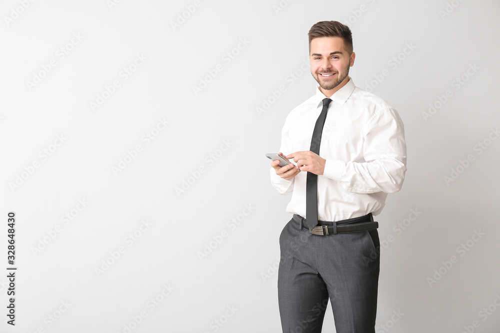 Young businessman with mobile phone on light background Young businessman with mobile phone on light background