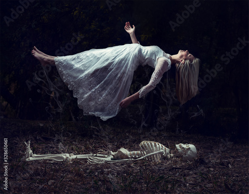 Levitation image of a woman rising from a skeleton on dead leaves