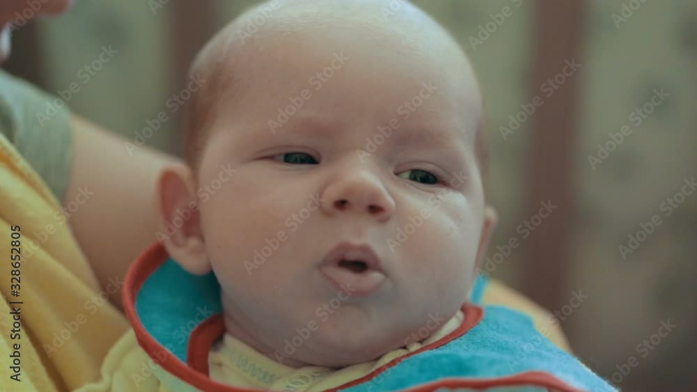Portrait of charming toddler with chubby cheeks resting vertically in his mother's arms. Mother holding her new born baby boy. Mom and child. Portrait of charming toddler with chubby cheeks resting vertically in his mother's arms. Mother holding her new born baby boy. Mom and child.