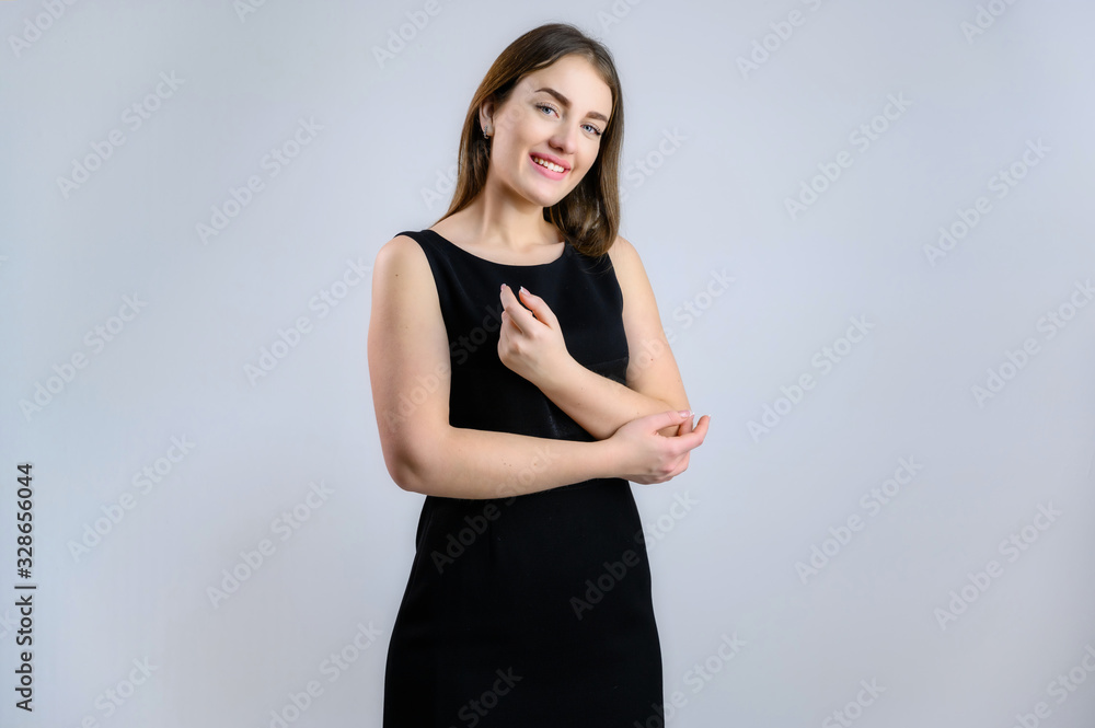 Generic concept of a pretty Caucasian woman. A model stands in front of the camera with a smile in a black dress on a white background. Generic concept of a pretty Caucasian woman. A model stands in front of the camera with a smile in a black dress on a white background.