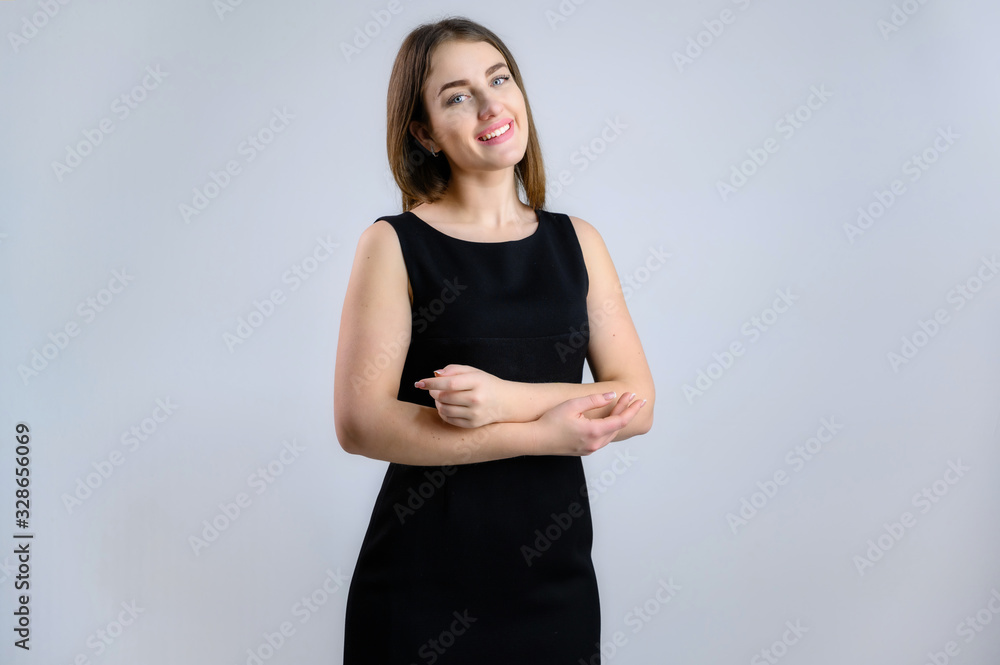 Generic concept of a pretty Caucasian woman. A model stands in front of the camera with a smile in a black dress on a white background. Generic concept of a pretty Caucasian woman. A model stands in front of the camera with a smile in a black dress on a white background.