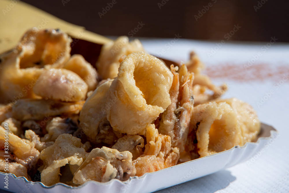 Paper cone filled with italian FRITTO MISTO, deep fried fish and shellfish. Typical take away delicacy from a street kiosk in the Emilia Romagna region of Italy.
