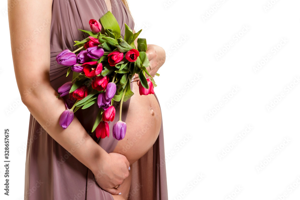 Pregnancy. Pregnant woman holding tulips in her hands near her bare belly