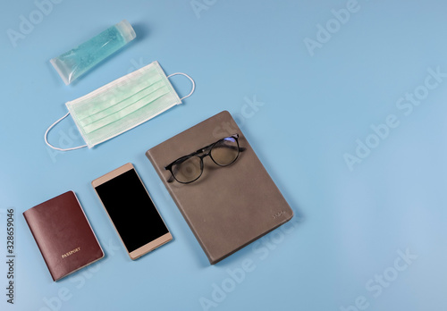 flat lay of business traveling accessories with face mask and sanitizer  on blue background ,protection from corona virus or COVID-19 during traveling concept with copy space