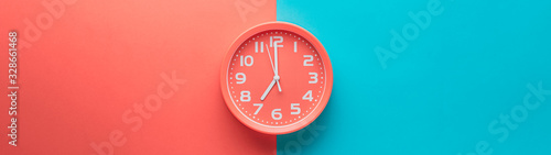 Red clock alarm clock on colored background divided vertically into red and green color web banner: planning or working time concept