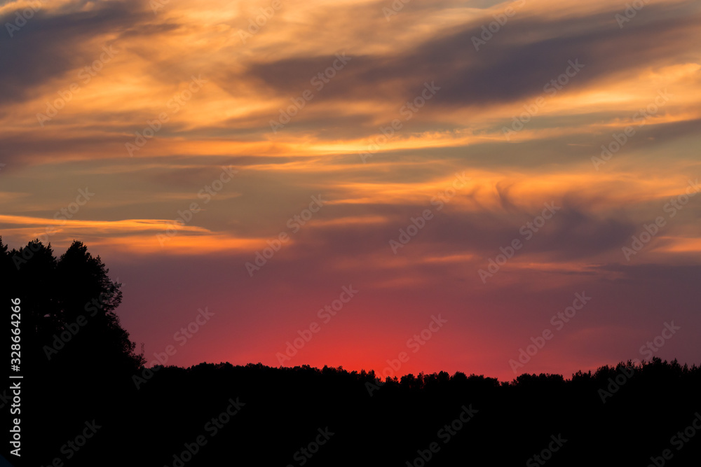 A fiery sunset over a distant forest A fiery sunset over a distant forest