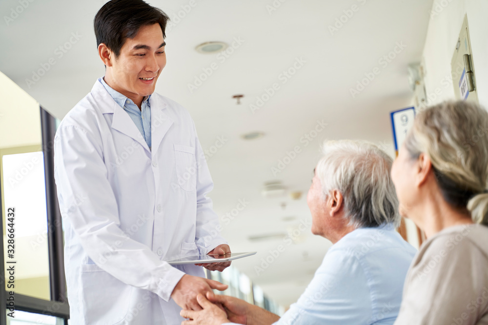 Obraz premium young asian doctor shaking hands with senior patient