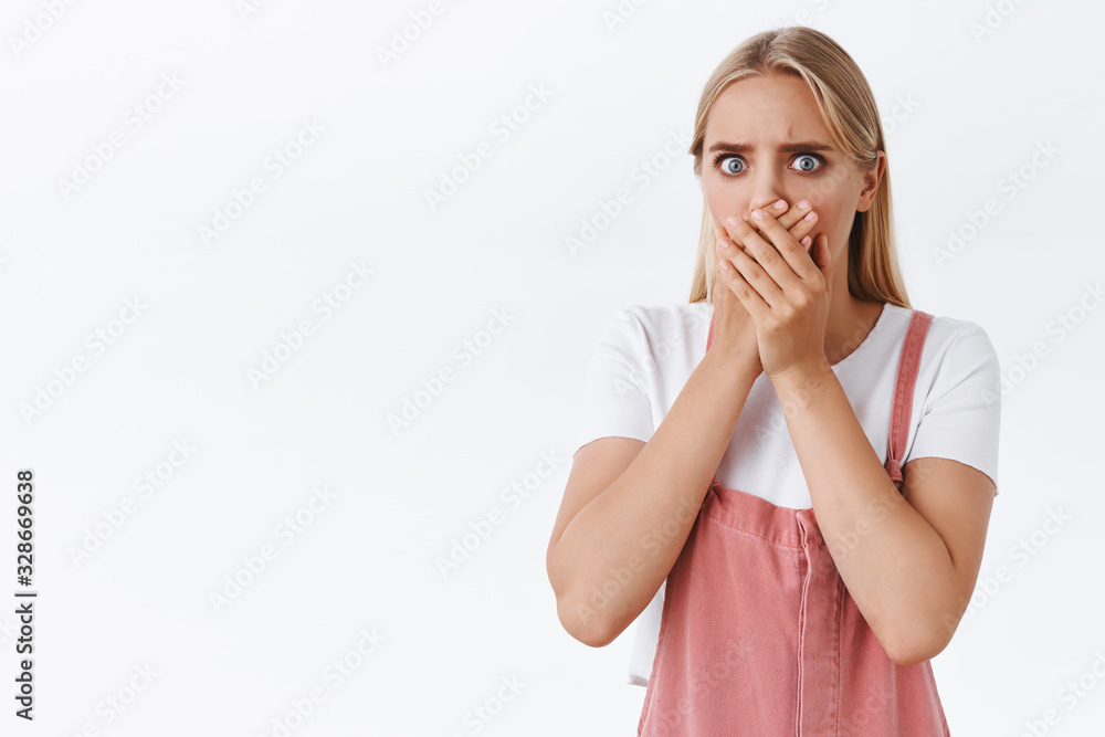 Shocked and disgusted young uneasy blond girl in pink overalls, t-shirt, gasping cover mouth with palm from fear and panic, stare camera upset, standing distressed and troubled white background Shocked and disgusted young uneasy blond girl in pink overalls, t-shirt, gasping cover mouth with palm from fear and panic, stare camera upset, standing distressed and troubled white background