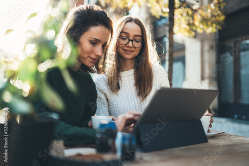 Obraz na płótnie Freelancer communicate on project, girls drink coffee, friends shopping online on wifi tablet in cafe outdoor. Students studies on internet w salonie