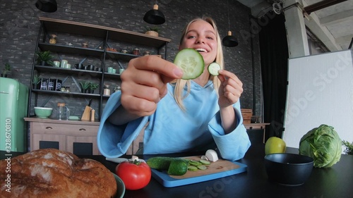 Young beautiful blonde takes on videos as she cooks in the kitchen photo