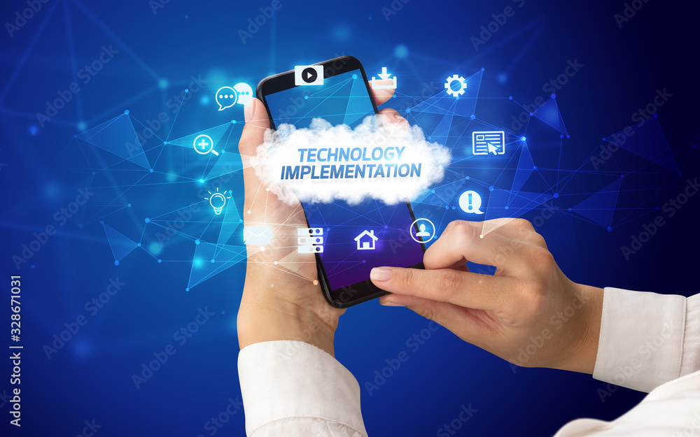 Female hand holding smartphone with TECHNOLOGY IMPLEMENTATION inscription, cloud technology concept Female hand holding smartphone with TECHNOLOGY IMPLEMENTATION inscription, cloud technology concept