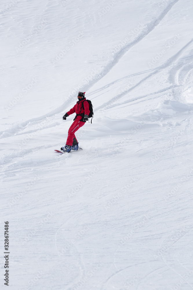 Snowboarder in red descends on snowy ski slope