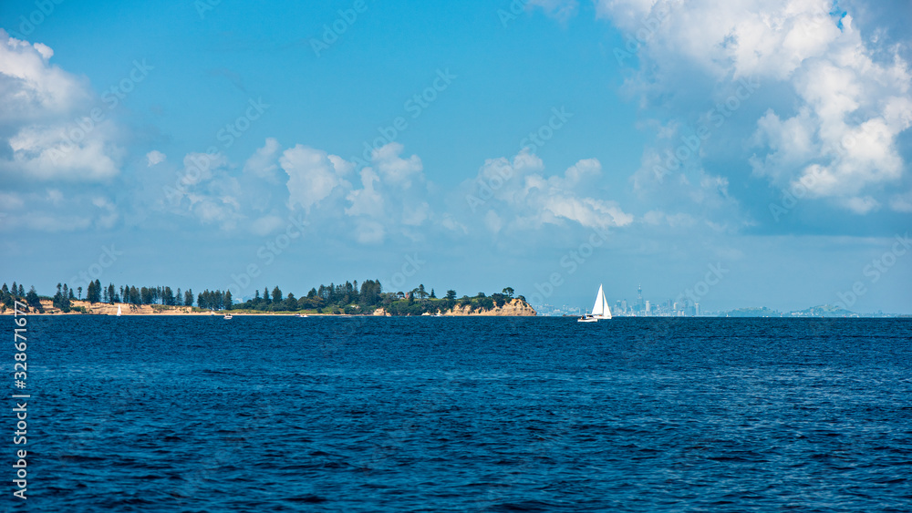 A sailboat on a tranquil blue sea on a cloudy day