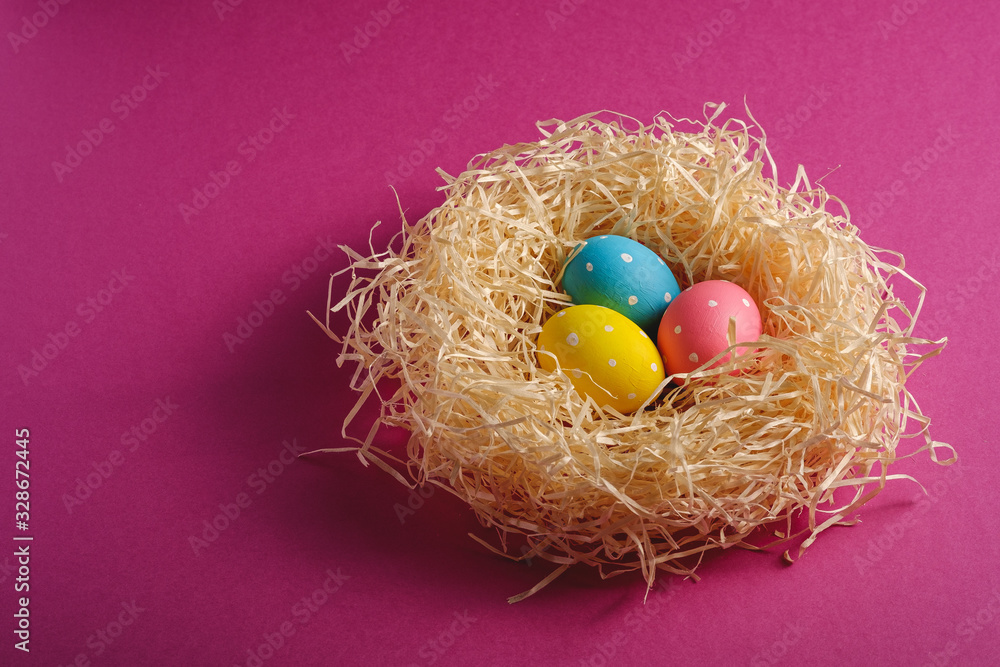 Colorful polka dot Easter eggs in wooden nest on pink purple plain background, greeting card, copy space, angle view Colorful polka dot Easter eggs in wooden nest on pink purple plain background, greeting card, copy space, angle view