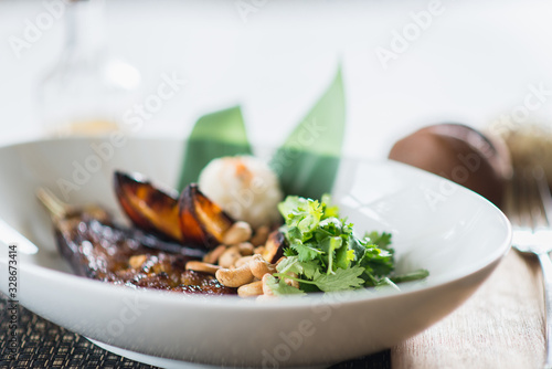 Asian cuisine, baked eggplant with nuts and rice in a deep plate on a table in a restaurant.