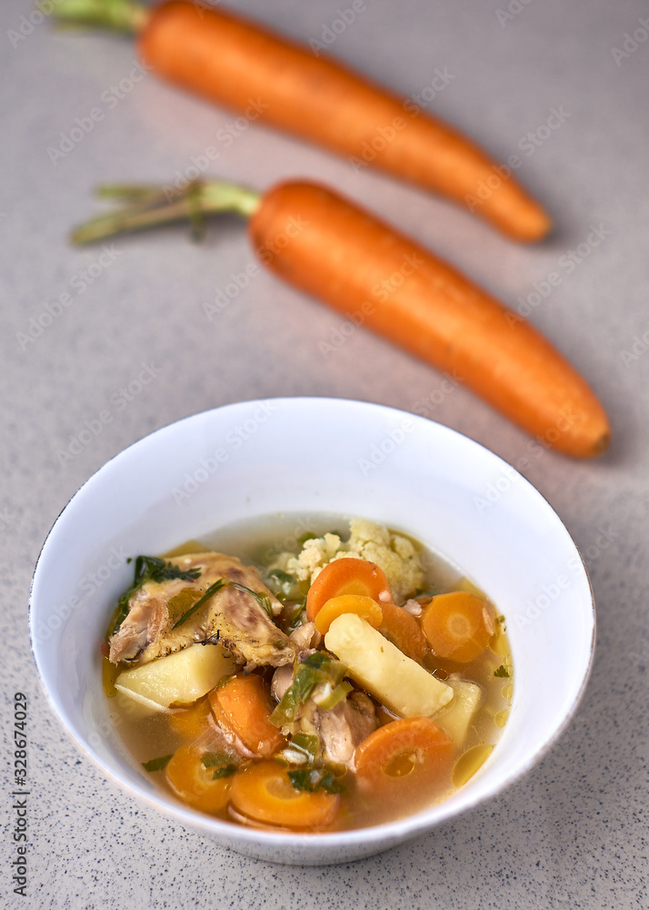 Chicken vegetable soup in white bowl, Indonesian food on a gray background Chicken vegetable soup in white bowl, Indonesian food on a gray background