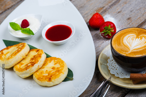 Traditional breakfast with coffee and cheesecakes  cottage cheese pancakes on a plate with syrup and jam.