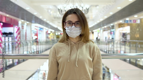 Young woman in medical mask at the mall. The masked woman protects herself from the epidemic of the Chinese virus. The camera approaches a woman 2019-nKoV