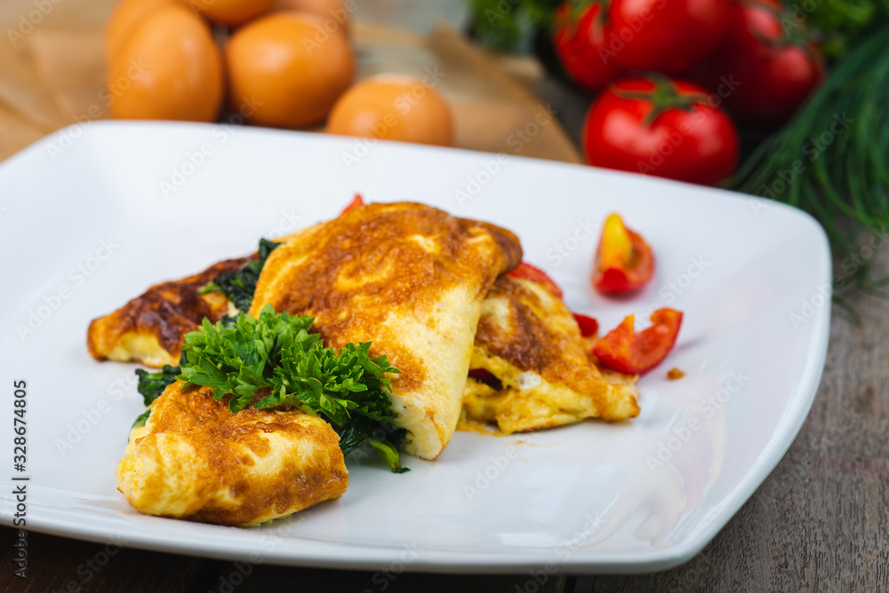 Traditional omelet with vegetables, spinach, tomatoes and herbs on a wooden table in a restaurant. Traditional omelet with vegetables, spinach, tomatoes and herbs on a wooden table in a restaurant.