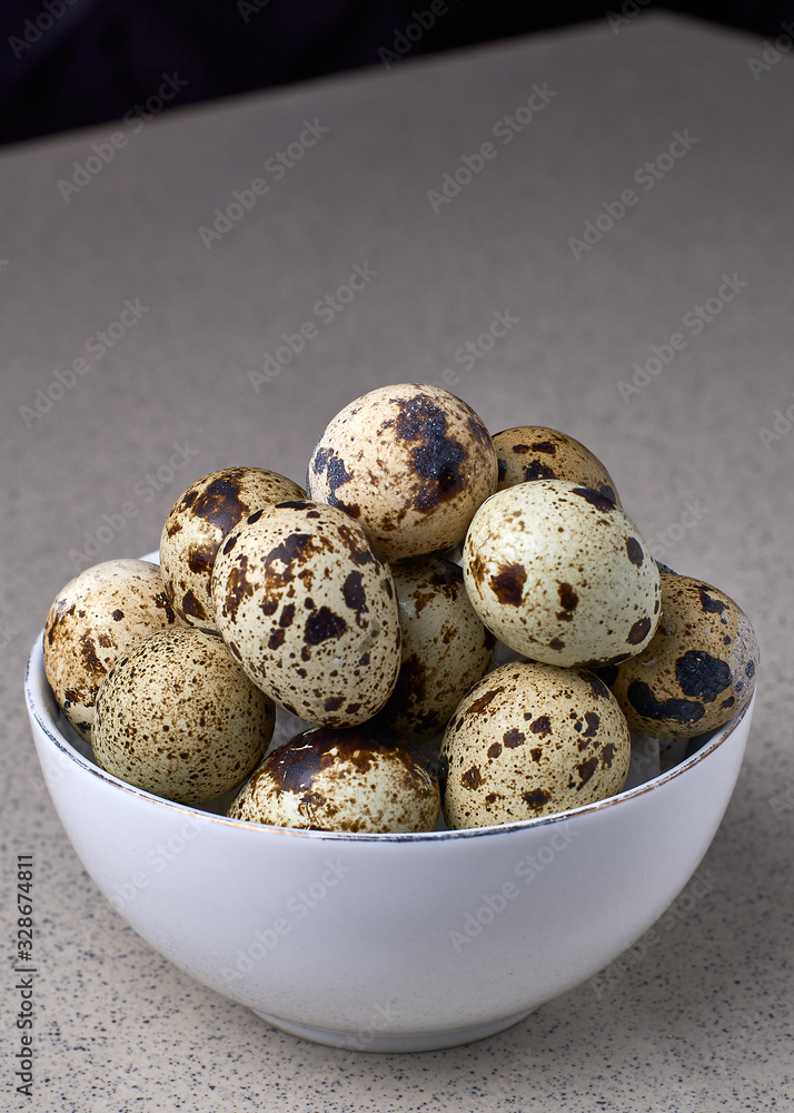 quail eggs in a white bowl on gray background