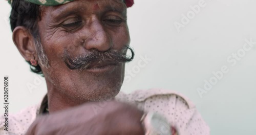 Close-up of old Indian man wearing a traditional colourful Rajasthani turban as he talks to someone off camera looking sideways and make hand gesture in an animated, intense and thoughtful discussion 