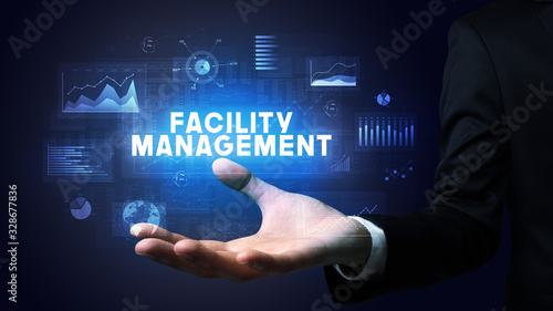 Hand of Businessman holding FACILITY MANAGEMENT inscription, business success concept