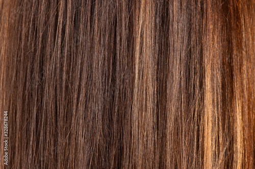 Glossy brown hair texture, background. Close view of long straight women's hair. Hair care concept.