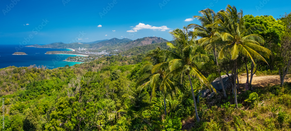 Panorama of the tropical island of Phuket with green trees on the foreground and perfect sandy beaches on the horizon, Thailand