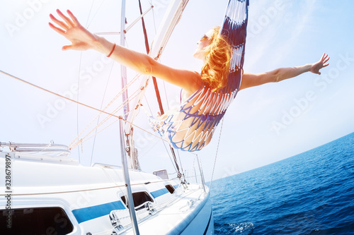 Young woman enjoys tropical sailing in the hammock set on the yacht