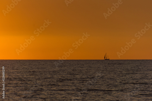 Sunset with a sailing boat on the horizon © Markus