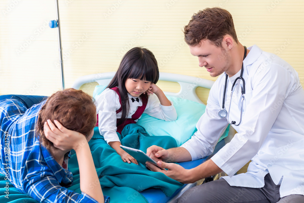 Obraz premium Pediatrician (doctor) man recording and taking information to tablet with little girl patient and mother in hospital.