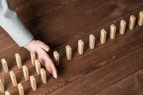 Businesswoman protecting dominoes from falling