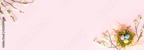Canvas Print Stylish background with colorful easter eggs isolated on pink pastel background with blooming cherry branches