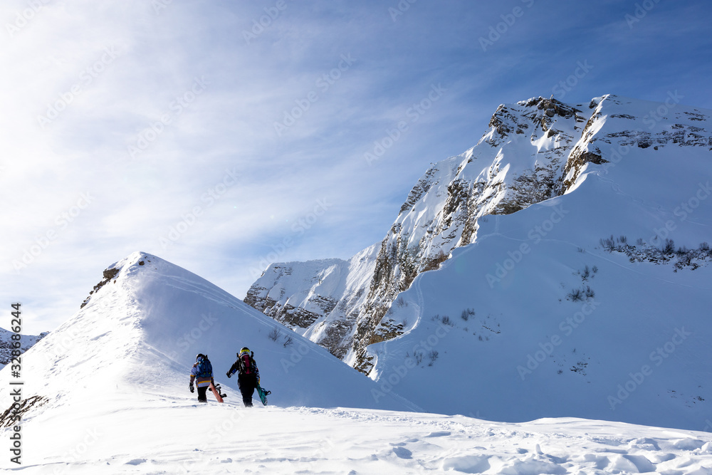 Two Snowboarders walking to the mountain.