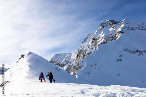 Two Snowboarders walking to the mountain.