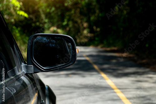 Traveling on the asphalt road in forest on the side mirror open light break signal.